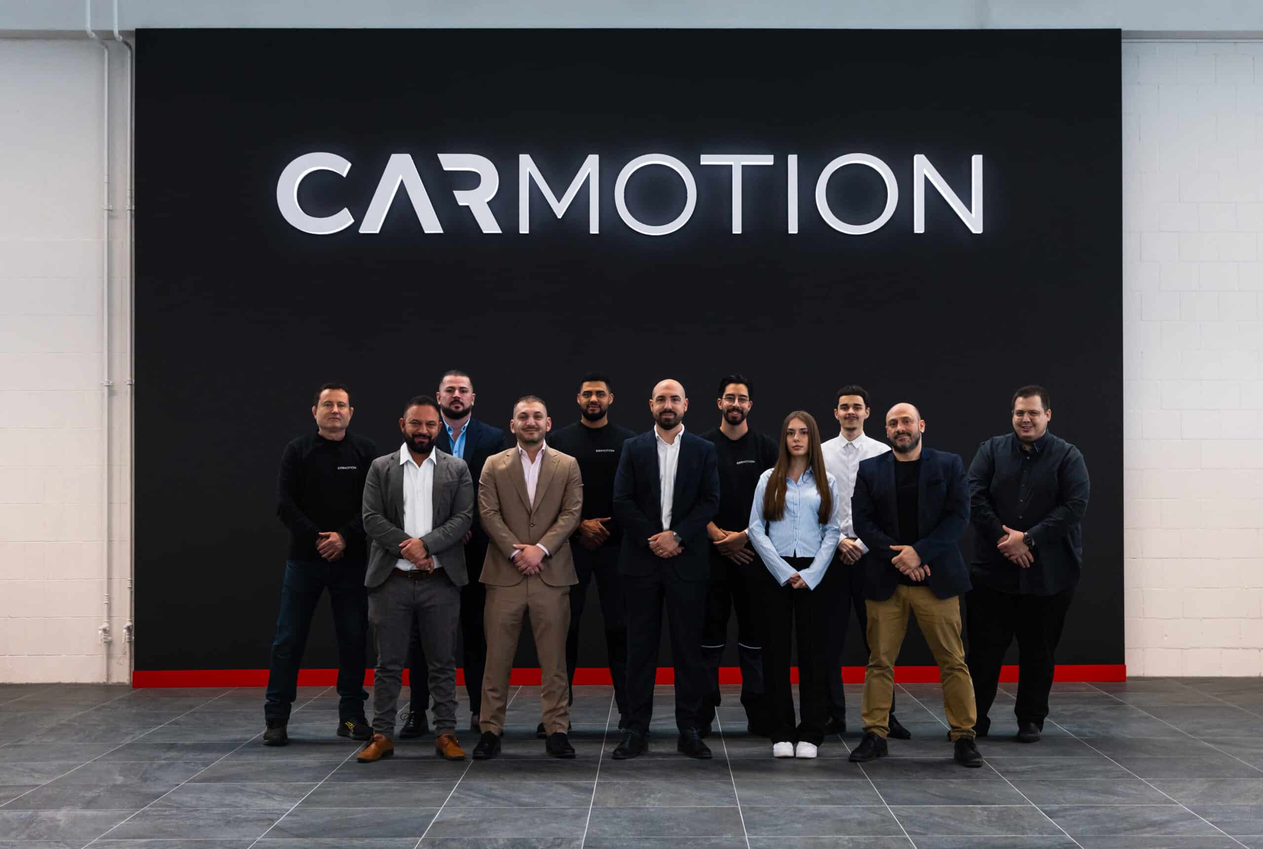 CARMOTION Team vor dem CARMOTION Schriftzug im Showroom